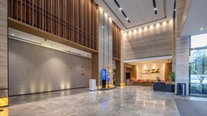 A spacious lobby with a polished marble floor, a reception desk, and a large vertical wooden panel on the left.