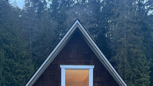 Une petite maison de plain-pied, dotée d’un toit à pignon et d’une lucarne.