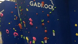 Una pared de escalada con presas de distintos colores y el nombre de la marca 'GADROCK'.