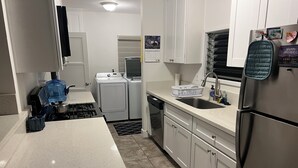 A modern kitchen with white cabinets, a stainless steel refrigerator, a sink, and a stove.