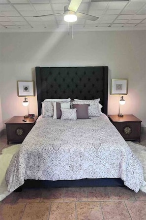 Una camera da letto con un letto grande, due comodini, una ventola a soffitto e un lampadario.