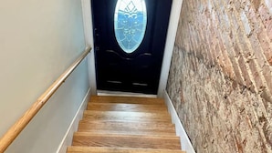 A wooden staircase with a handrail, leading to a door with a frosted glass window. - The Loft On Broad - Gadsden’s First Downtown Loft (Gadsden)