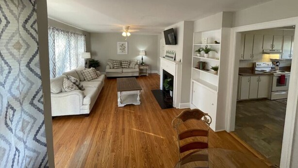 A living room with a sofa, coffee table, and a fireplace. There is a kitchen area with cabinets and a stove. - *Hidden Gem Close 2 Everything * (Gadsden)