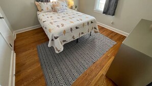A bedroom with a bed, a patterned rug, and a window with curtains. - *Hidden Gem Close 2 Everything * (Gadsden)
