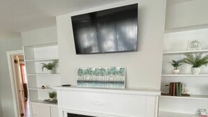 A living room with a fireplace, white shelves, and a flat-screen TV mounted above the mantel. - *Hidden Gem Close 2 Everything * (Gadsden)