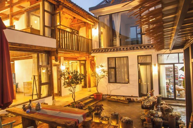A multi-story building with a balcony, a wooden deck, and a variety of potted plants.