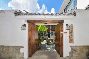 A traditional entrance with a wooden gate, a tiled roof, and a sign with Chinese characters.