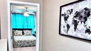 A bedroom with a bed, a world map on the wall, and a door leading to another room. - * Comfy Condo close to everything in Prattville * (Prattville)
