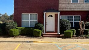 A two-story building with a red brick facade and a small entrance porch. - * Comfy Condo close to everything in Prattville * (Prattville)