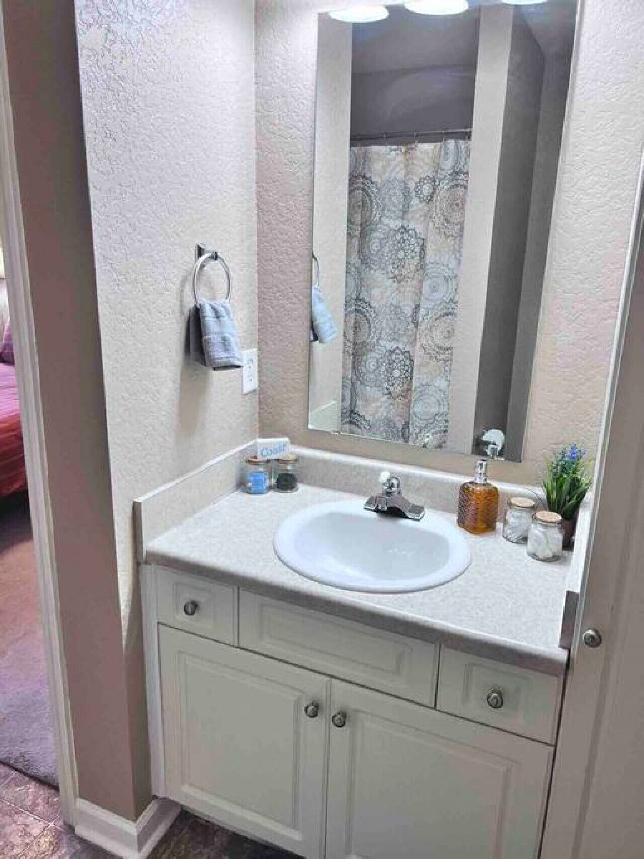 A bathroom with a white sink, a mirror, and a towel rack.