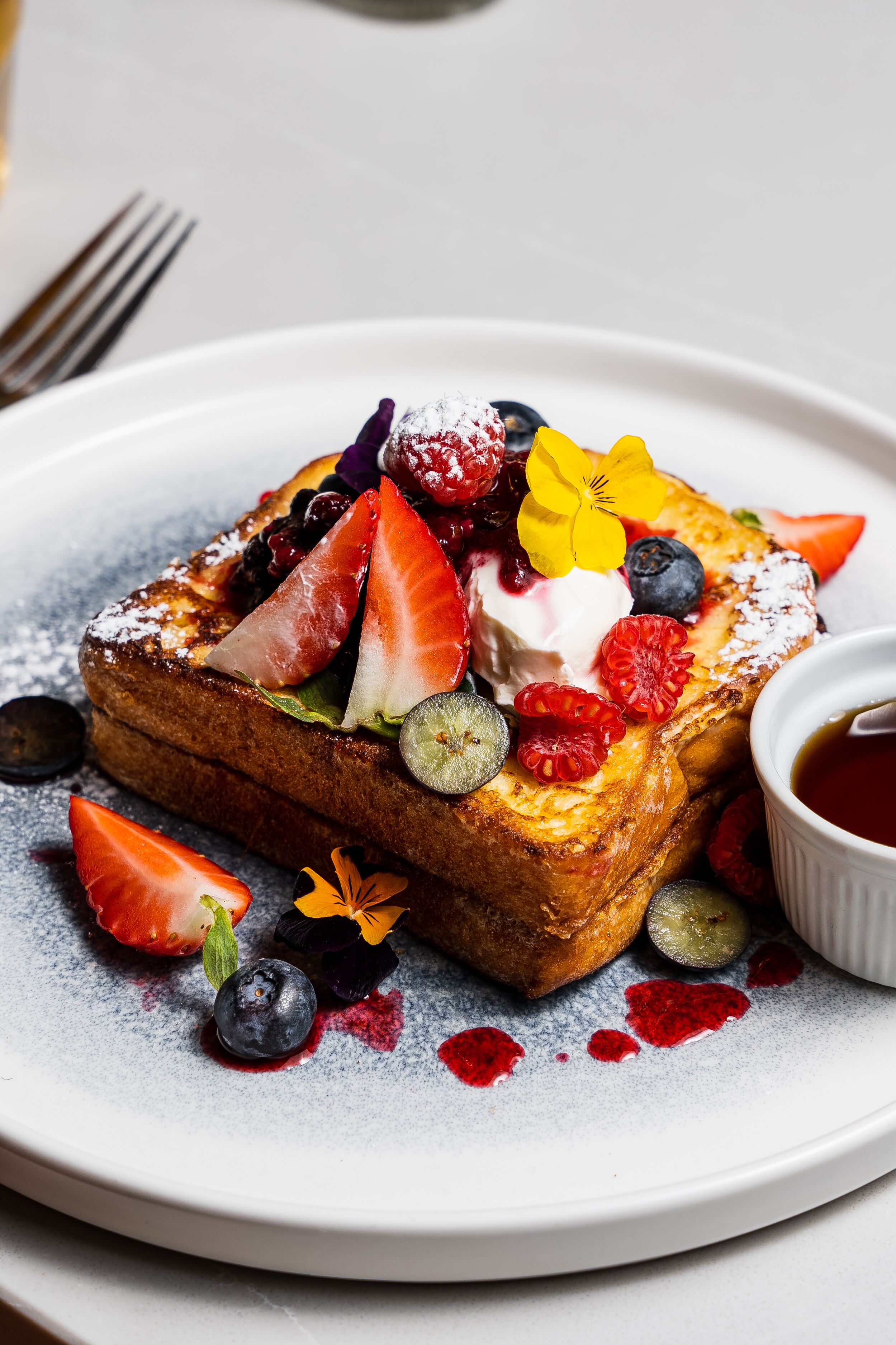 A plate of French toast with fruit and whipped cream.