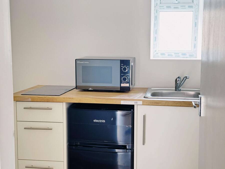 Una kitchenette compacta con microondas, pileta y lavavajillas.