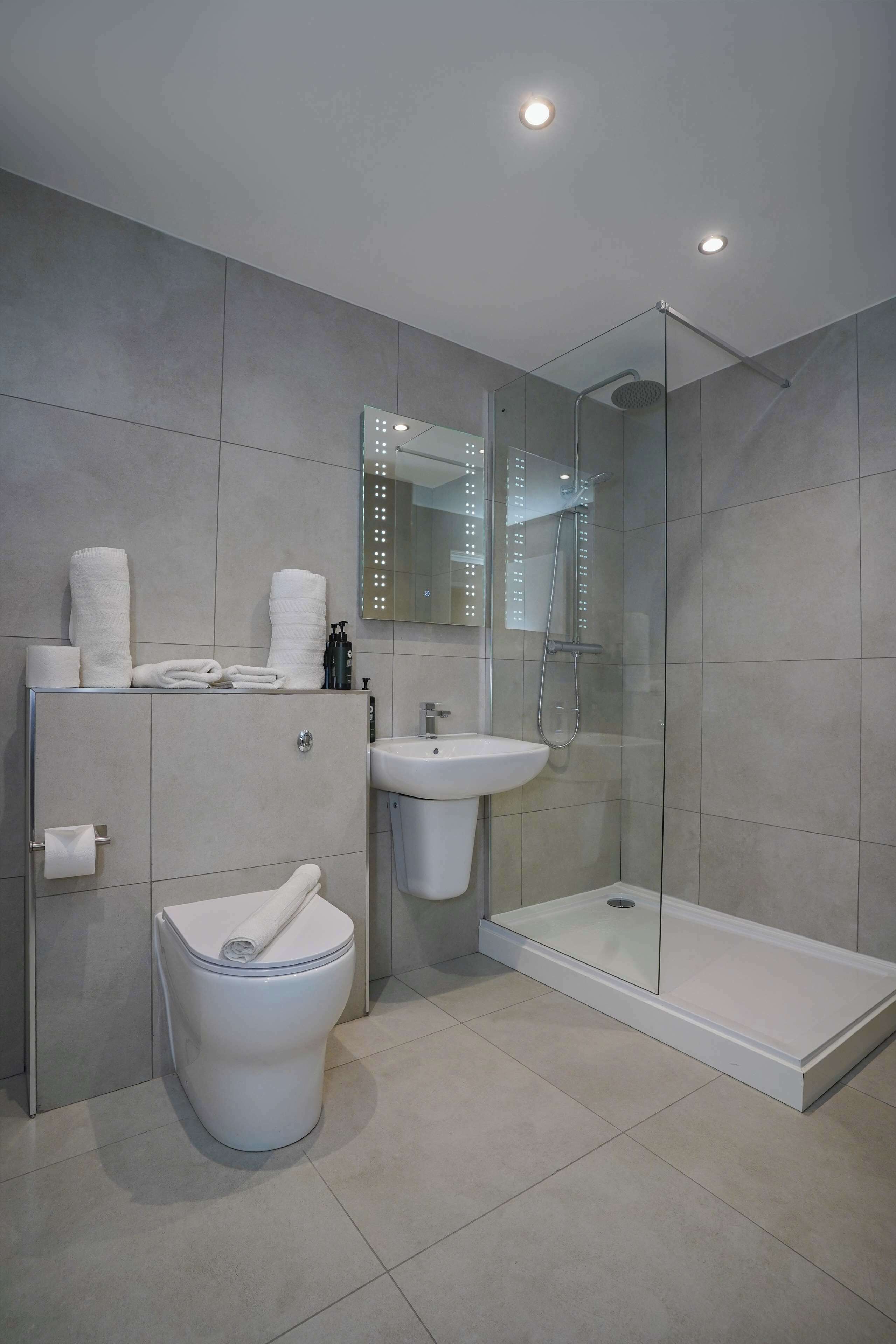 Een moderne badkamer met toilet, wastafel en douchecabine.