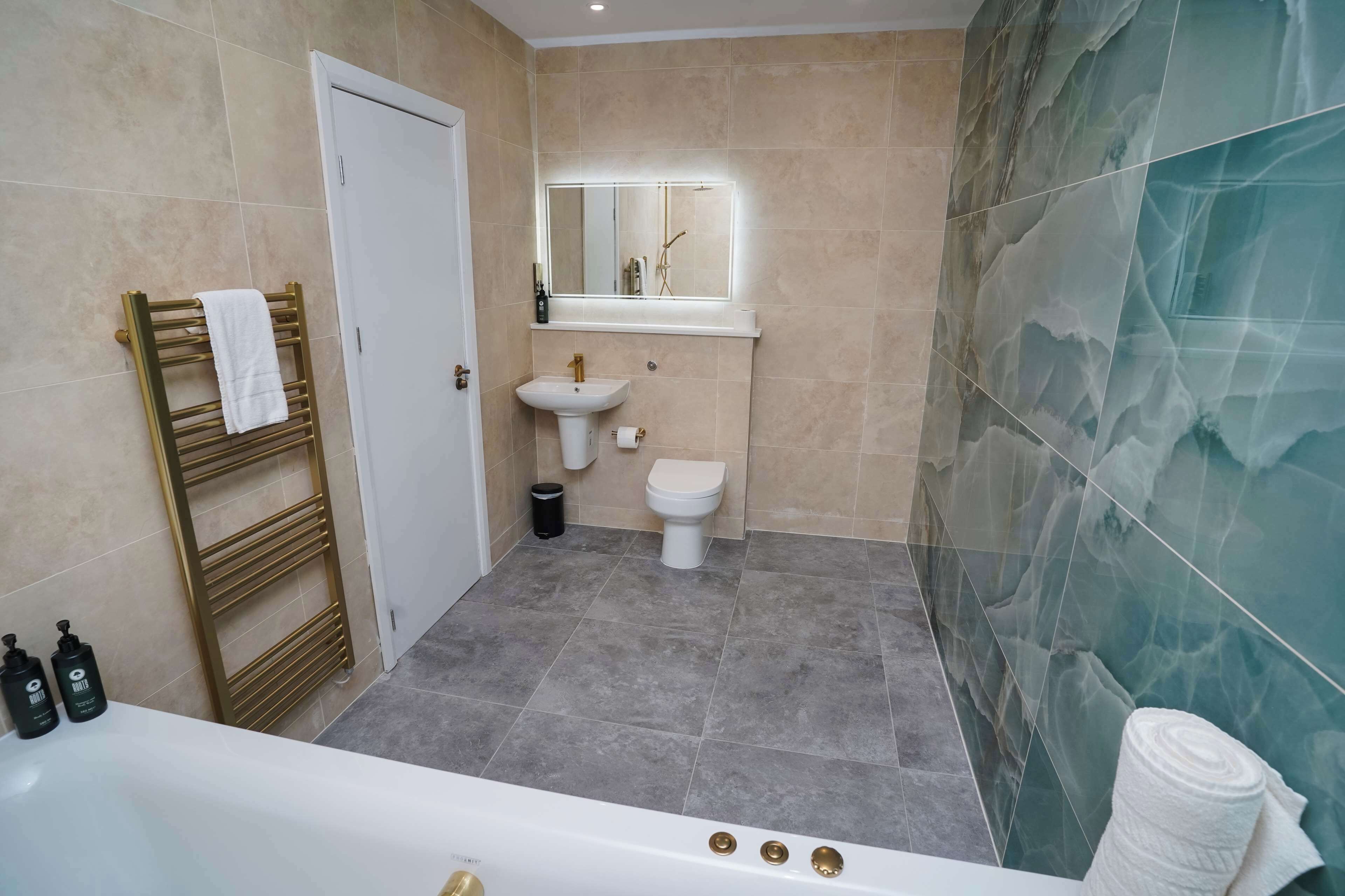 Un baño con bañera, lavamanos, inodoro y un perchero para toallas.