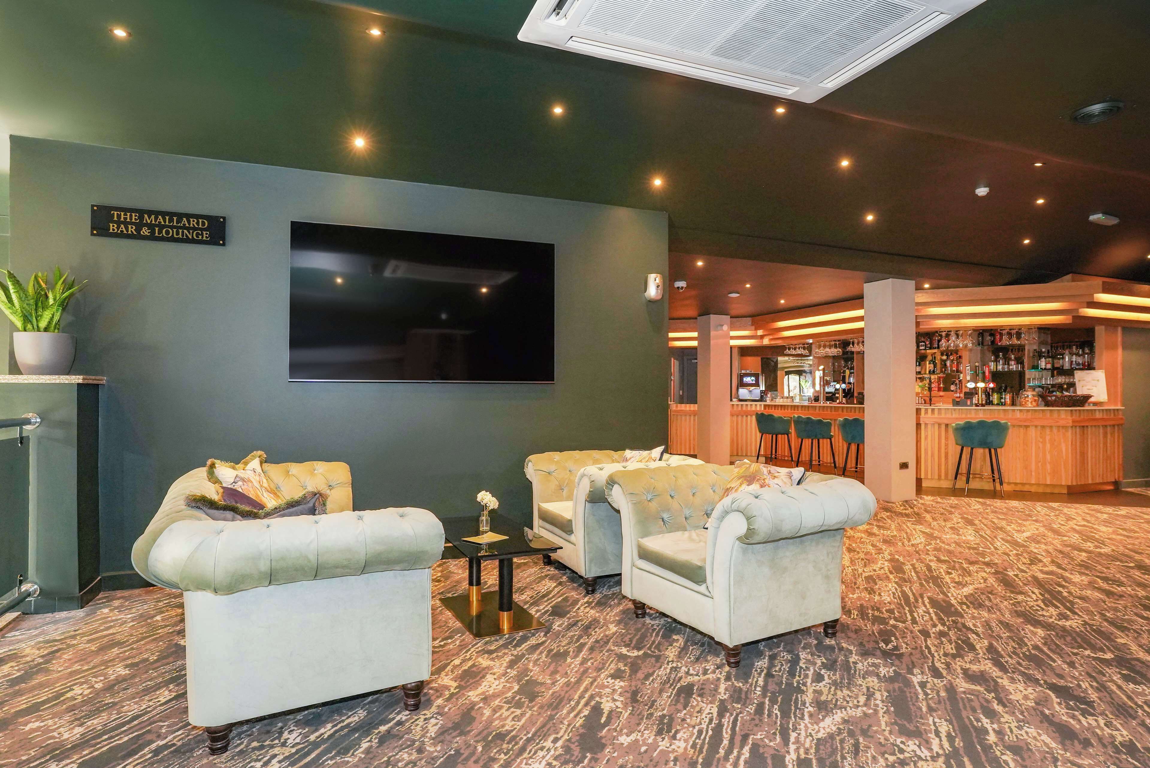 A lounge area with sofas, a TV, and a bar in the background.