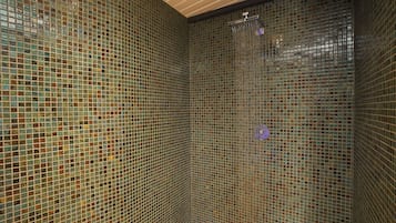 Enjoy a refreshing shower in this stylish bathroom with a mosaic tile wall and modern showerhead.