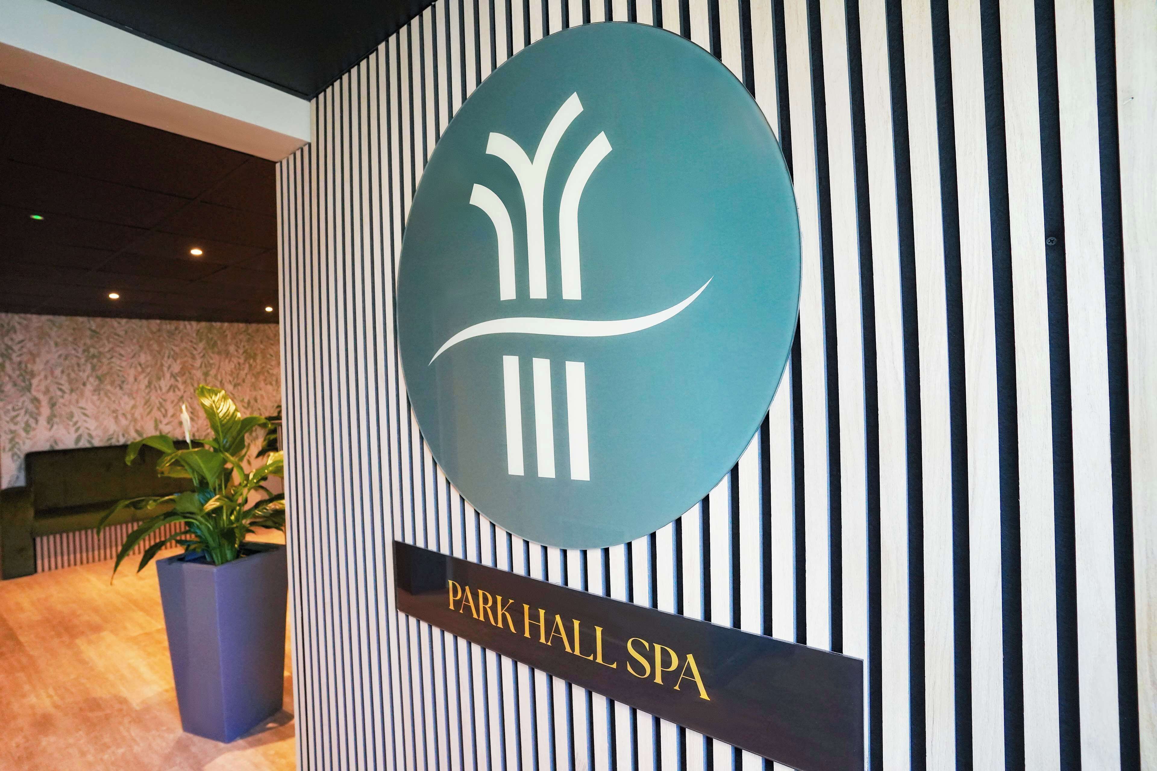 Una zona de recepción con un cartel que dice "Park Hall Spa" y un logo encima.