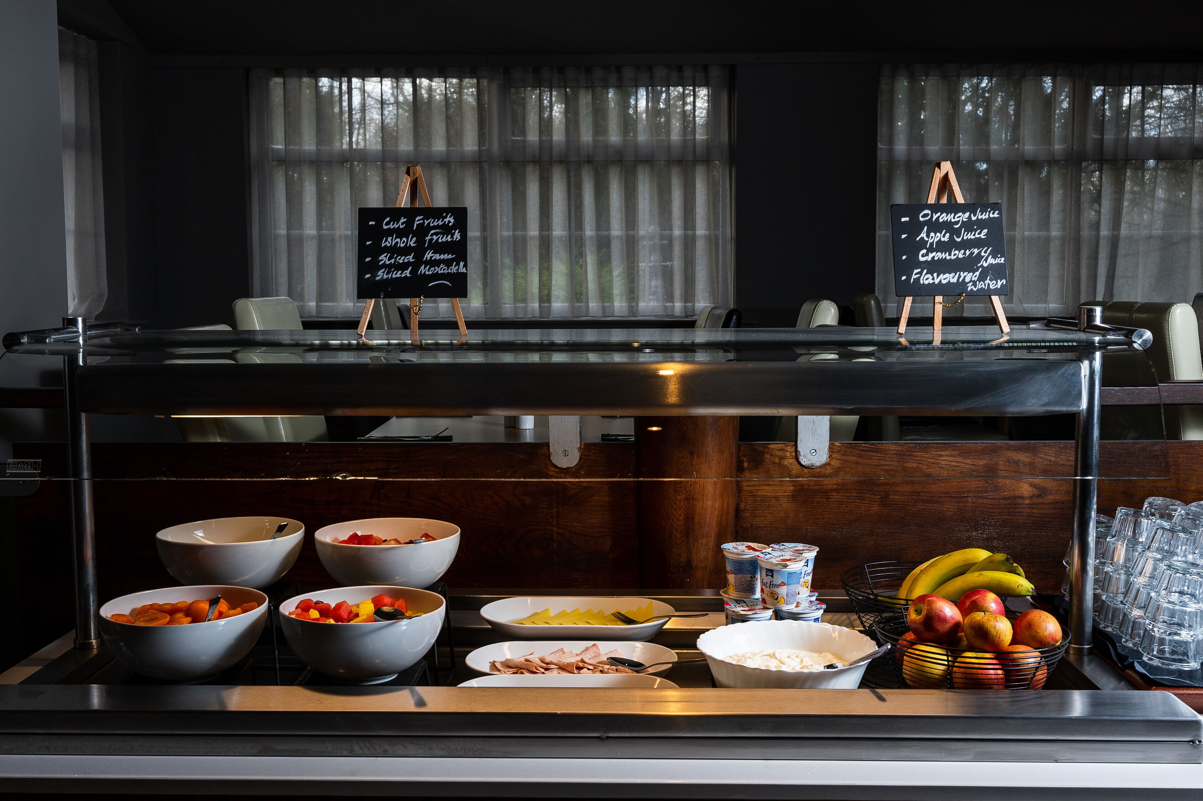 A buffet setup with various food items and a chalkboard menu listing options like orange juice and apple juice.