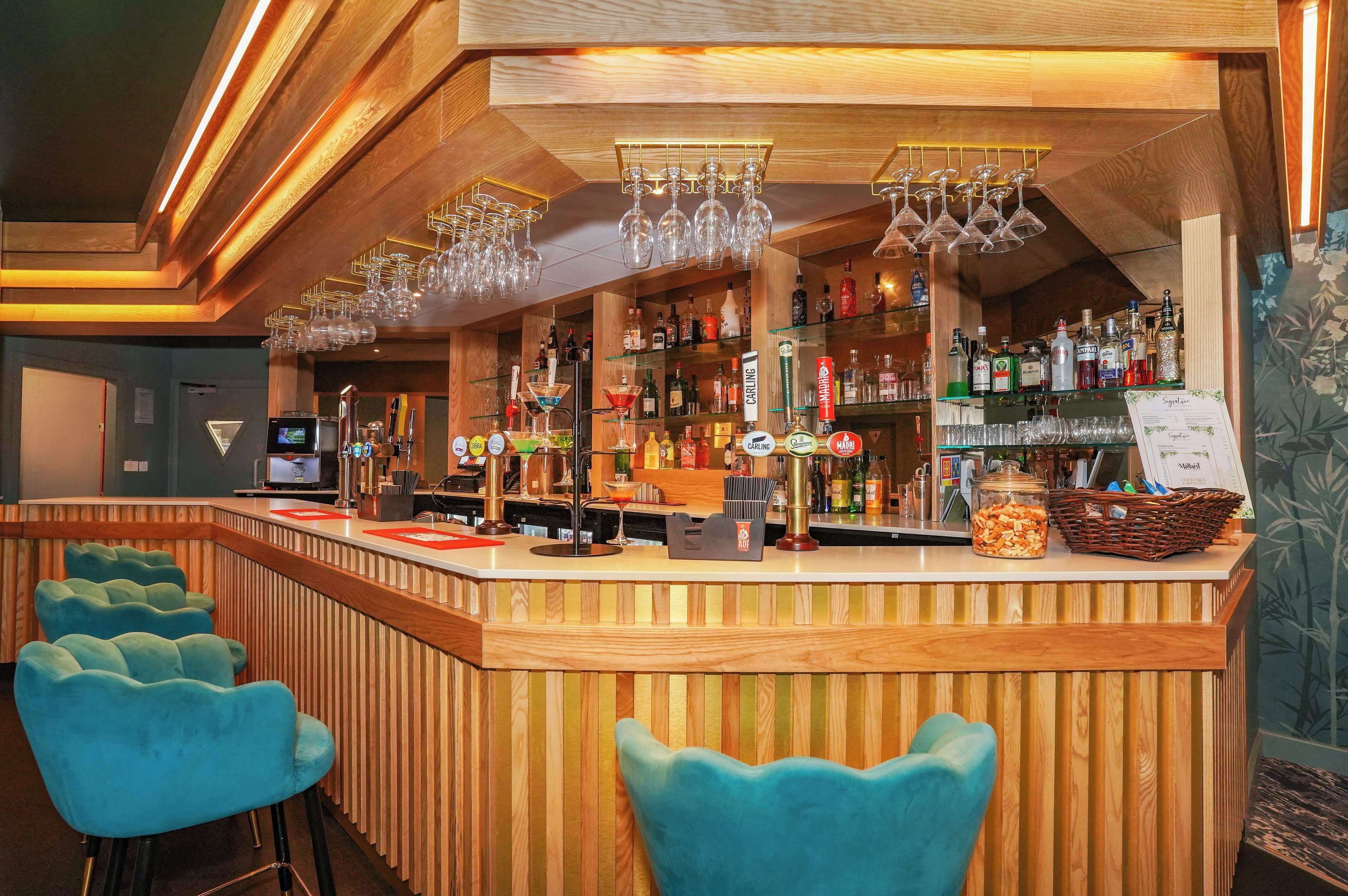 Eine Bar mit Holzwandverkleidung, einer Theke mit Speisekarte und blauen Sitzgelegenheiten.