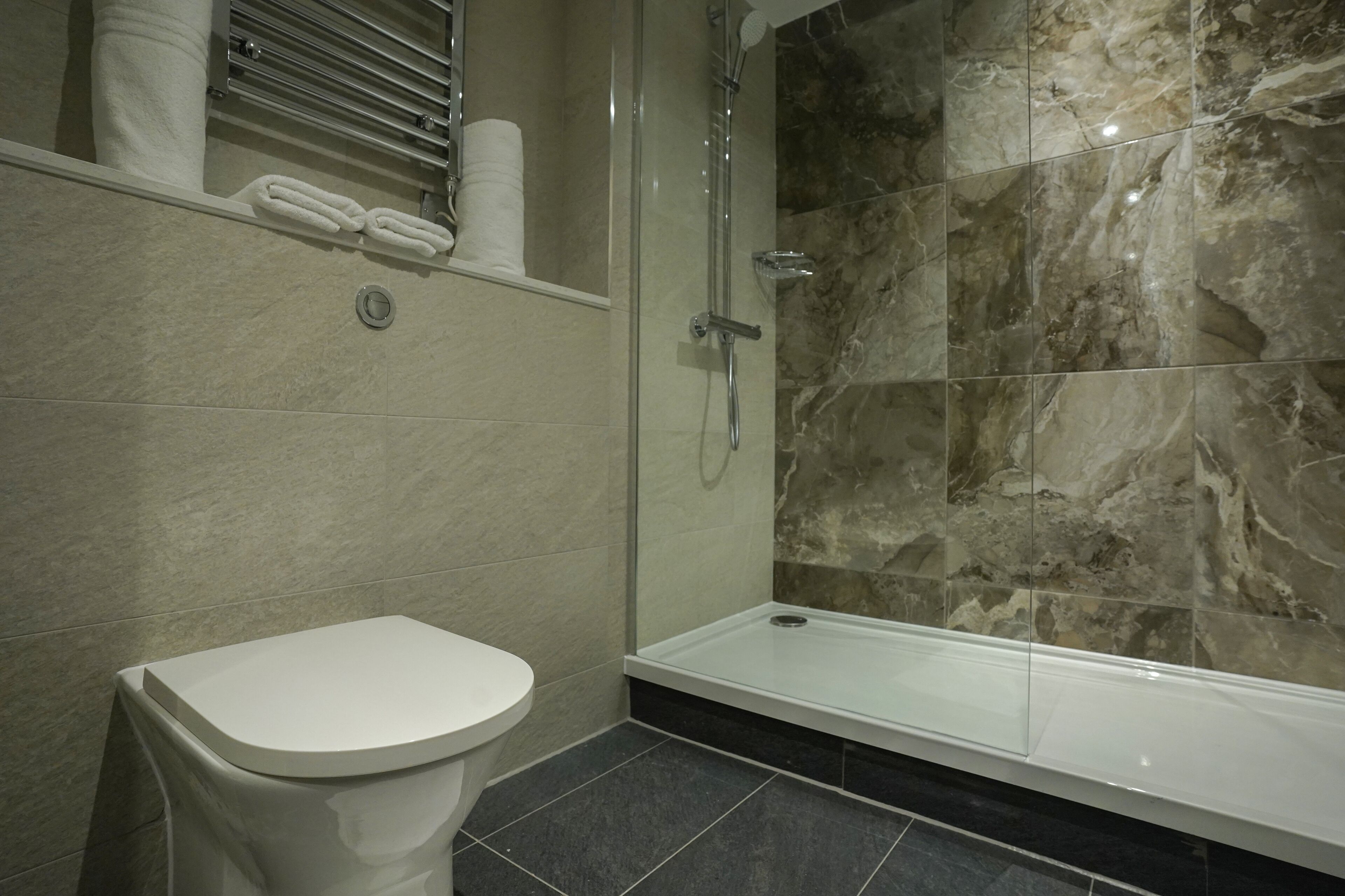 A modern bathroom with a toilet, a shower, and a glass-enclosed shower area.