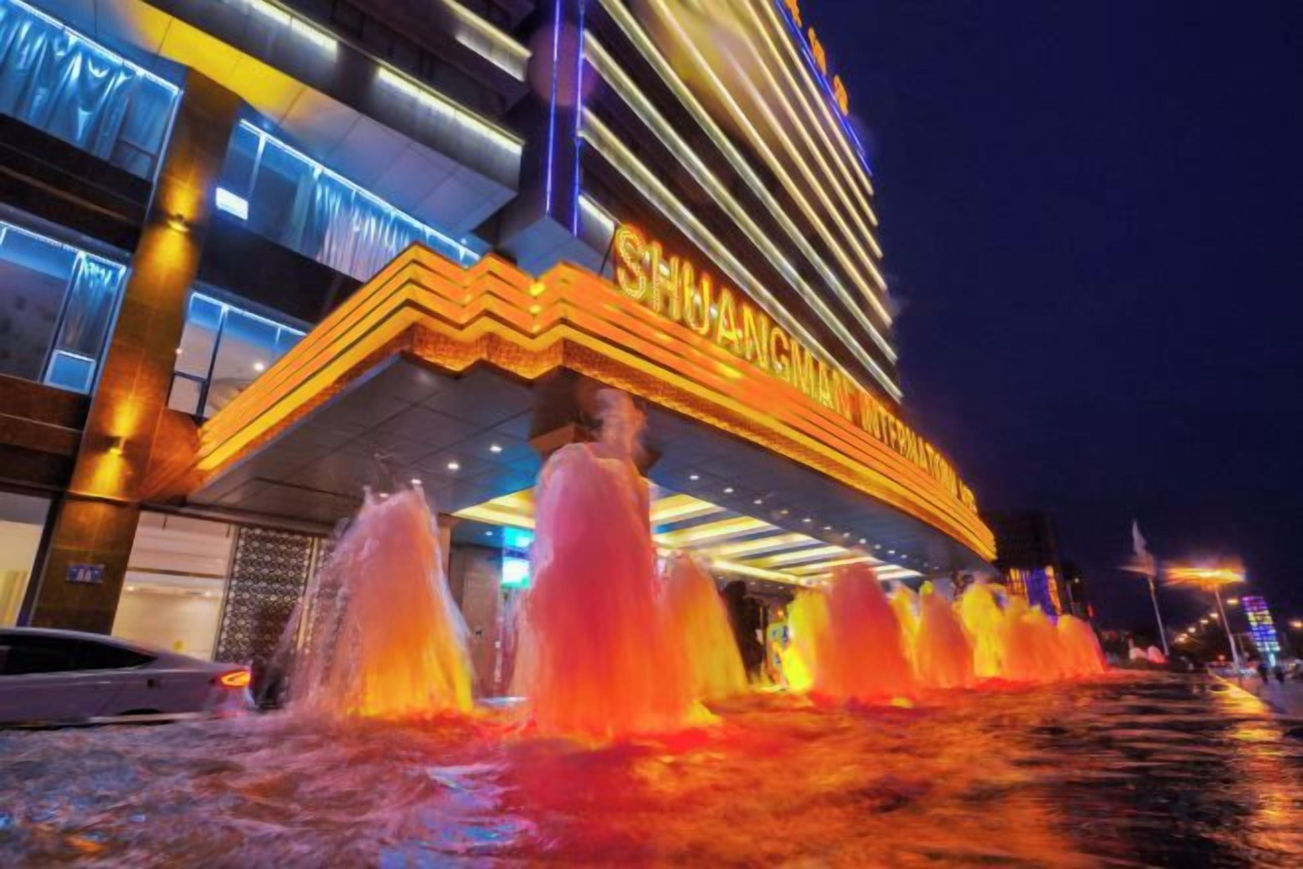 A hotel with a prominent entrance, a fountain display, and a well-lit facade.