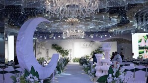 A stage with a large crescent moon decoration, a chandelier, and floral arrangements. - Shuangman International Hotel (Ordos)