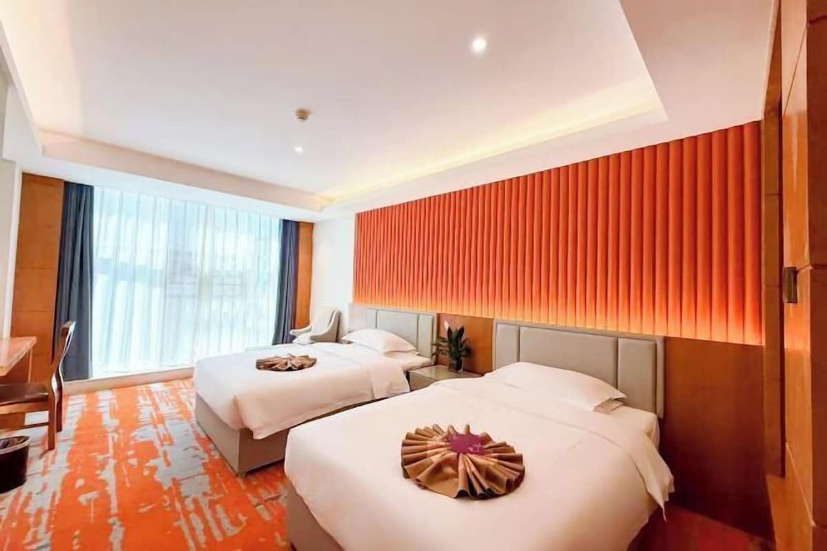 A hotel room with two beds, a large window, and a modern design.