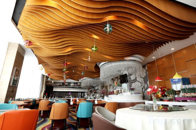 Un restaurante con una decoración moderna, que presenta un diseño de techo singular y una zona de bar central.