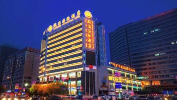 A multi-story hotel with illuminated signage, a prominent entrance, and a busy street in the background.