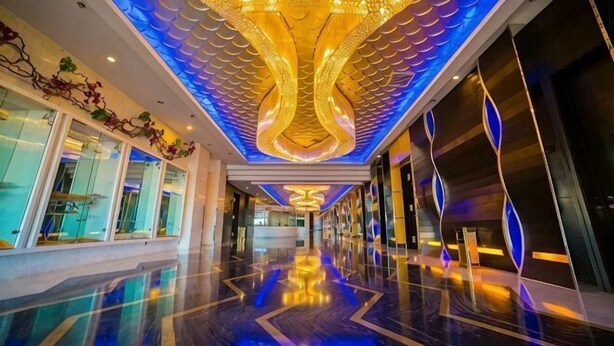 A hotel lobby with a reflective floor, a large chandelier, and a modern ceiling design. - Shuangman International Hotel (Ordos)