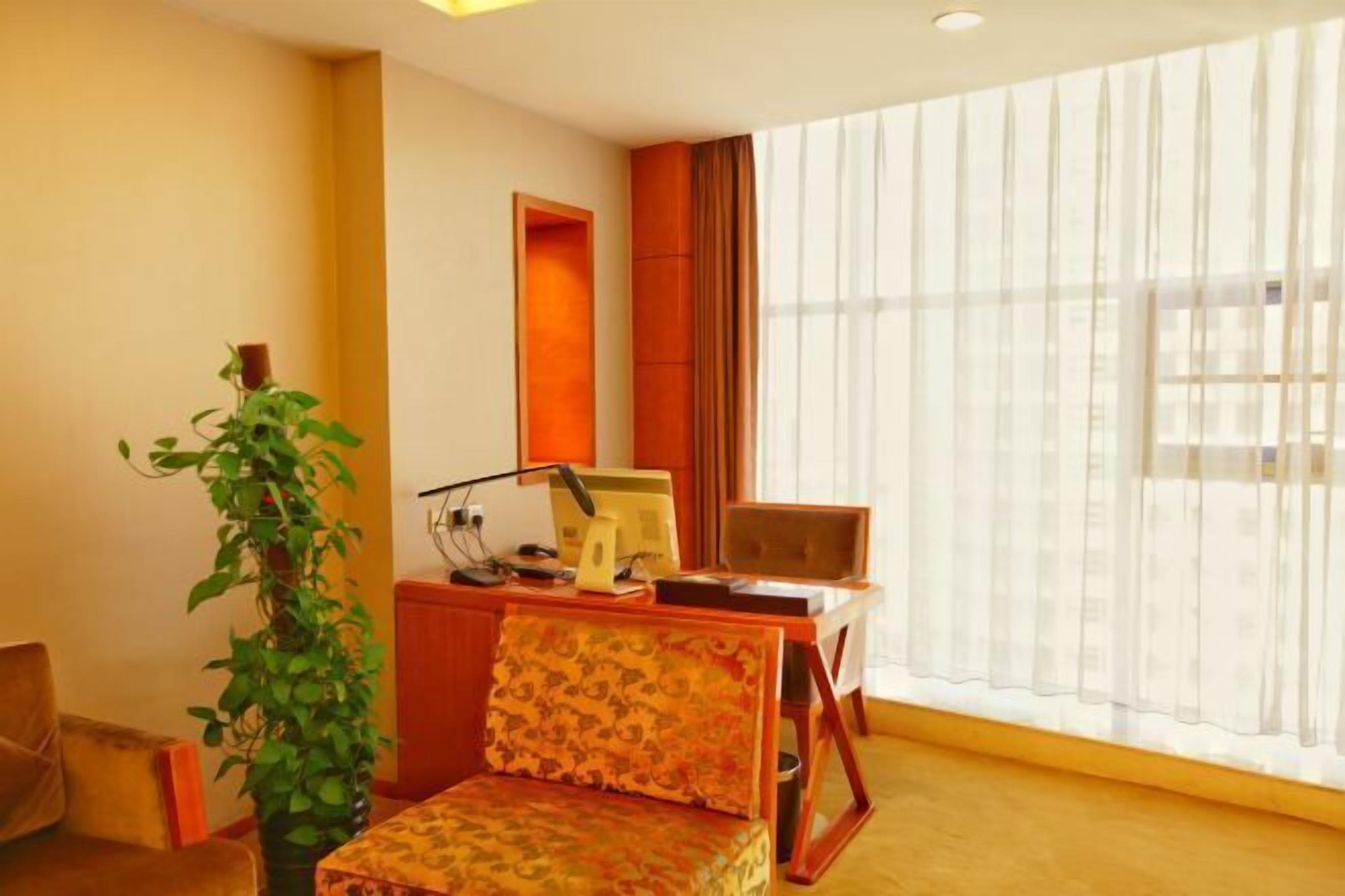 A room with a desk, chair, and a large window with sheer curtains.