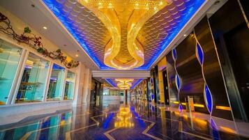 Un pasillo de hotel con piso reflectante, techo decorativo y grandes ventanales en un lateral.