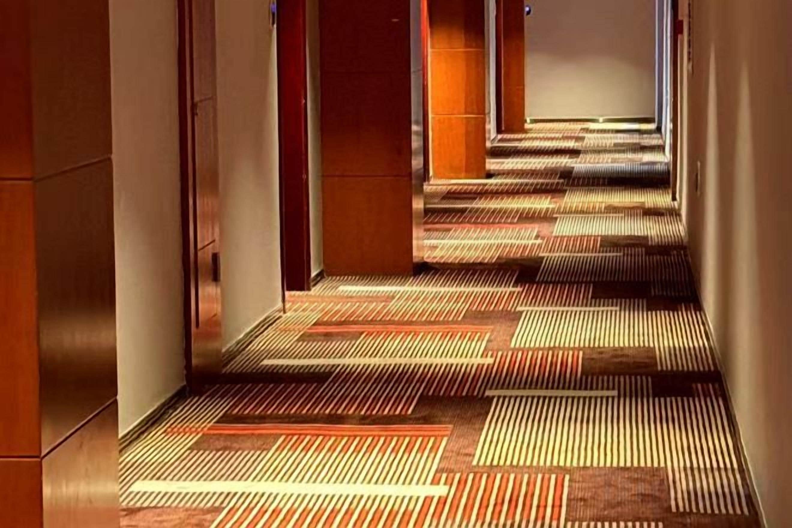 A corridor with patterned carpet and wooden walls.