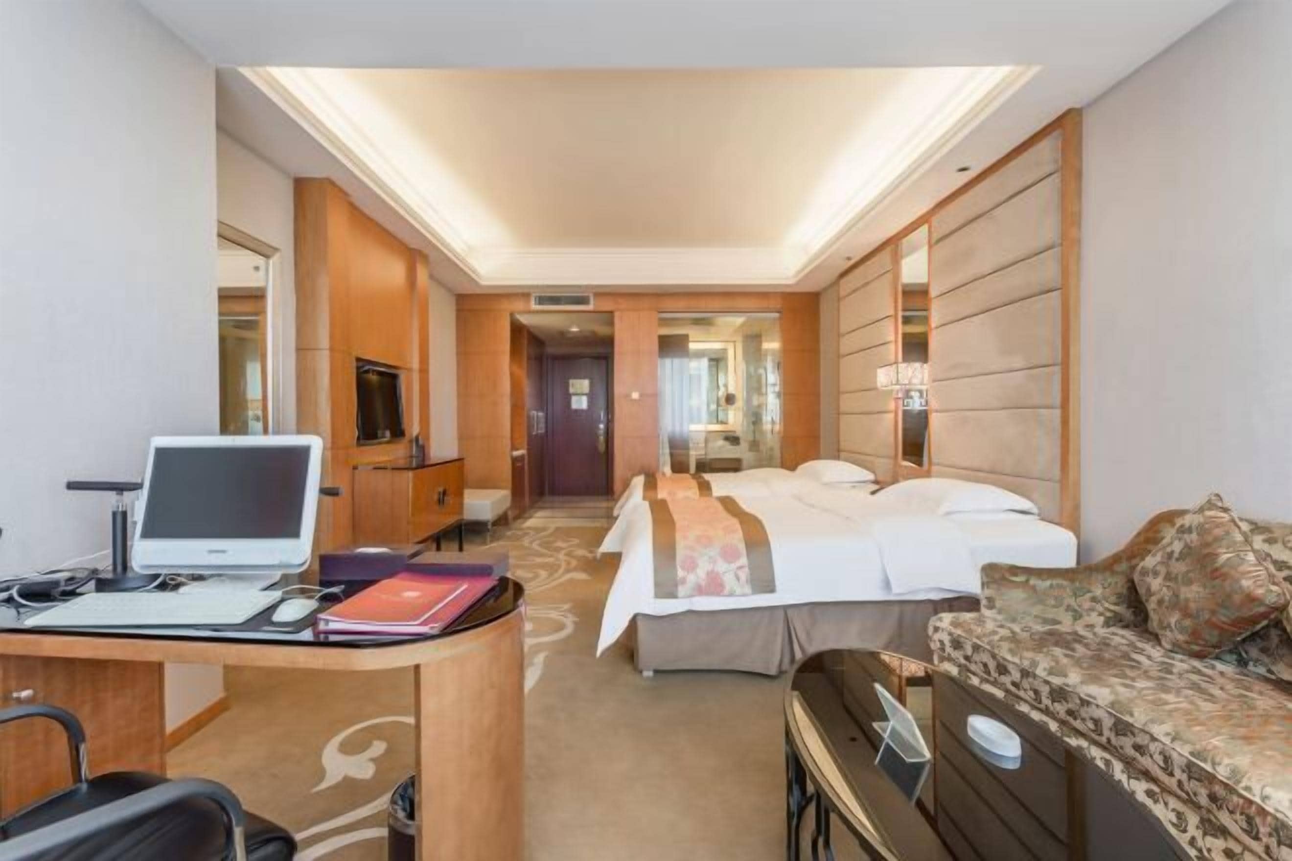Quarto de hotel com escrivaninha, computador, cama e sofá.