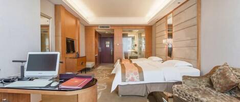 Quarto de hotel com escrivaninha, computador, cama e sofá.