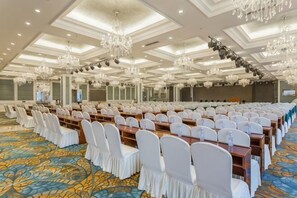 A large conference room with rows of tables and chairs, chandeliers, and a patterned carpet. - Shuangman International Hotel (Ordos)