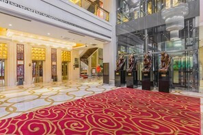 A hotel lobby with a red carpet, a staircase, and a glass facade. - Shuangman International Hotel (Ordos)