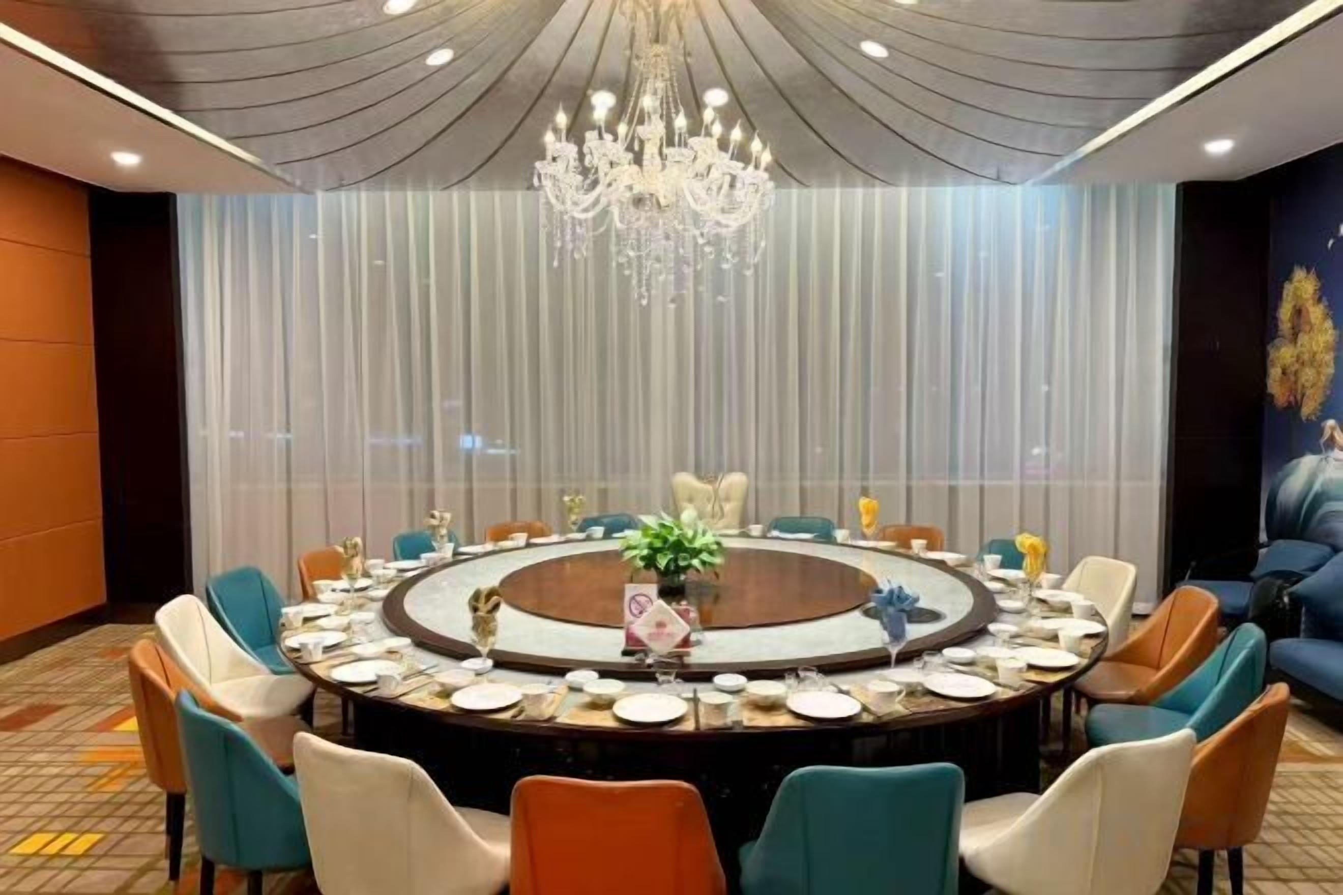 A conference room with a round table, chairs, and a chandelier.