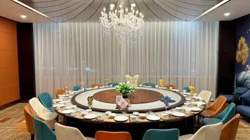 A conference room with a round table, chairs, and a chandelier.