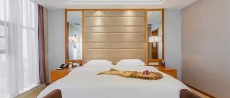 A modern hotel room with a large bed, a bedside table, a mirror, and a view of the city through large windows.