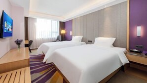 A hotel room with two beds, a desk, a TV, and a window with curtains.