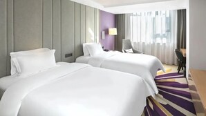 A hotel room with two beds, a desk, and a chair.