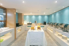 A buffet setup with multiple serving stations and a central table with plates and cutlery.