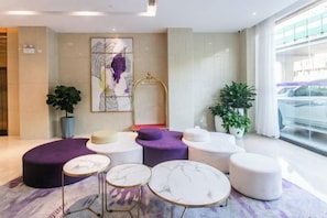 A modern lobby with round seating, a large mirror, and a view of the street.