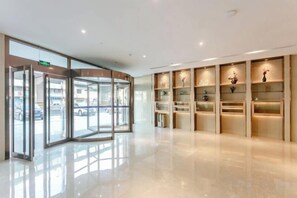 A hotel lobby with a revolving door, a reception desk, and a display of decorative items.