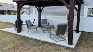 Un espacio de patio cubierto con una estructura de pérgola, con dos sillas y una mesita.