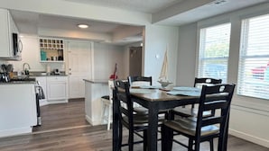 Una cocina moderna con armarios blancos, una mesa de comedor de madera y una decoración con forma de velero.