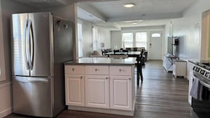 Una cocina moderna con un refrigerador de acero inoxidable, armarios blancos y una isla central.