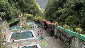 A pool area with multiple swimming pools surrounded by lush greenery and stone walls. - Casa Marluc (Machu Picchu)