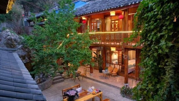 Un bâtiment traditionnel en bois doté d’un balcon, d’un espace extérieur aménagé pour s’asseoir et d’un jardin.